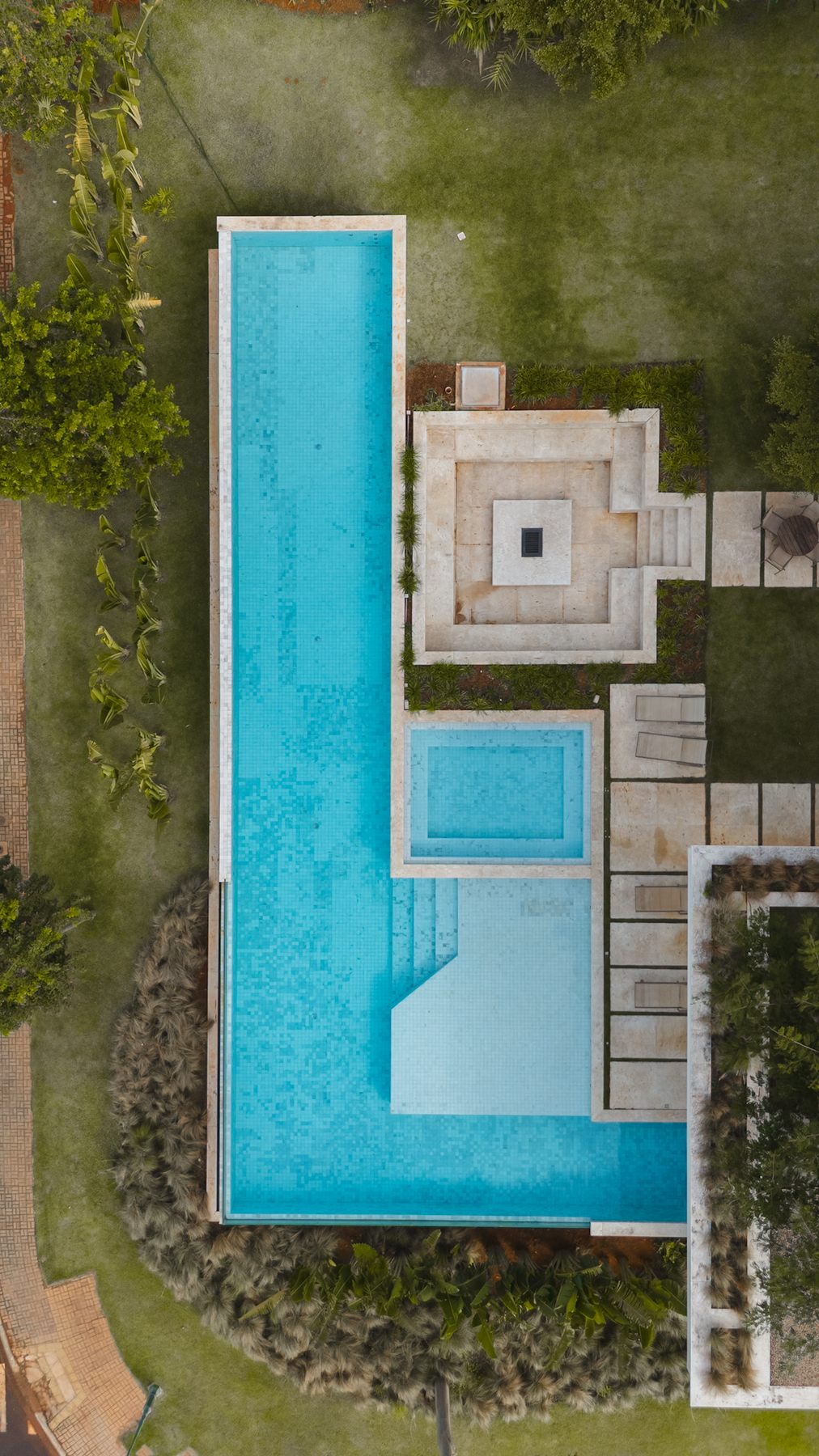Vista aérea de cima da piscina em L, da praça de fogo quadrada e do jardim